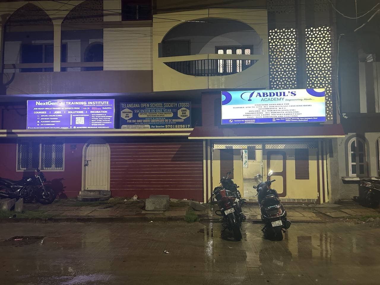 The building at night, the Abdul's Academy and NextGen AI Training Institute signboards lit side by side