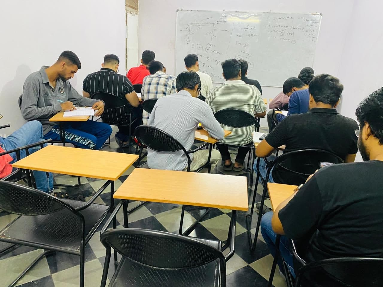 A class in session, students working at desks with the tutor alongside